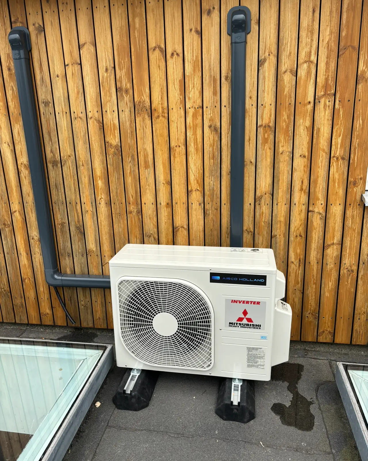 Een buitendeel van Mitsubishi Heavy Industries op een dakterras, tegen een houten gevel met twee grijze goten.