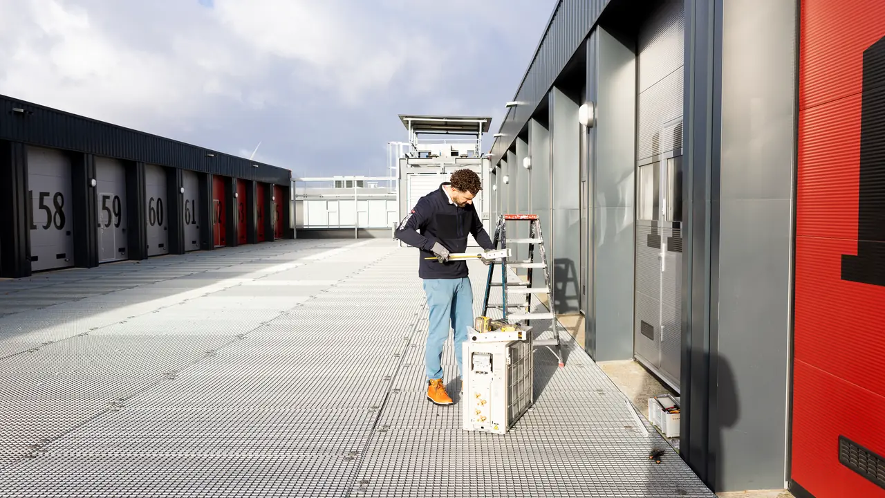 Rein aan het werk naast een nieuwe buitenunit op de galerij van een bedrijfsverzamelgebouw.