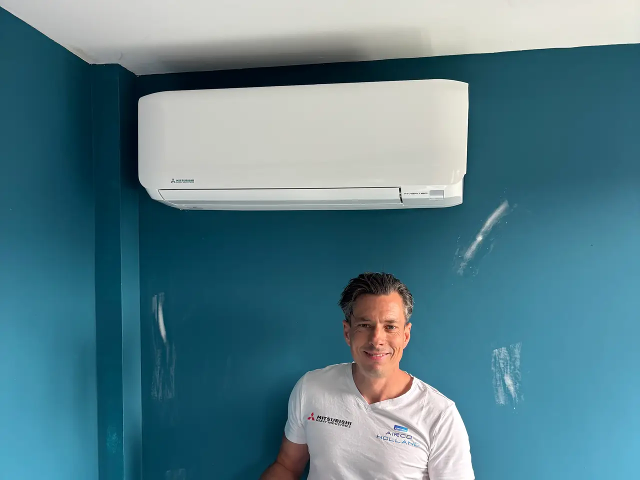 Peter staat met een kitpistool onder een nieuw wit binnendeel aan een petrolblauwe muur.