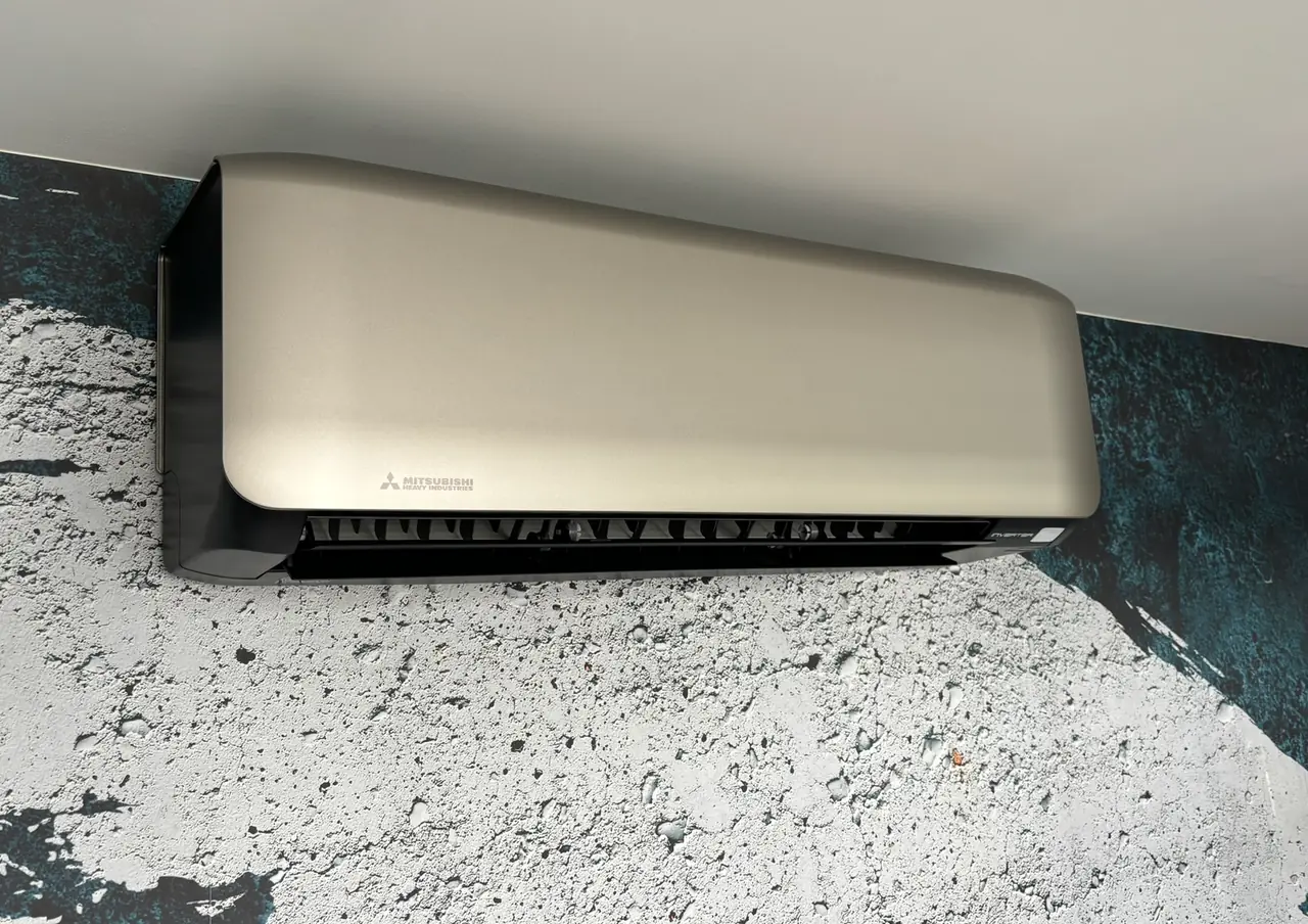 Een champagnekleurig binnendeel van Mitsubishi Heavy Industries aan een muur met behang in betonlook.