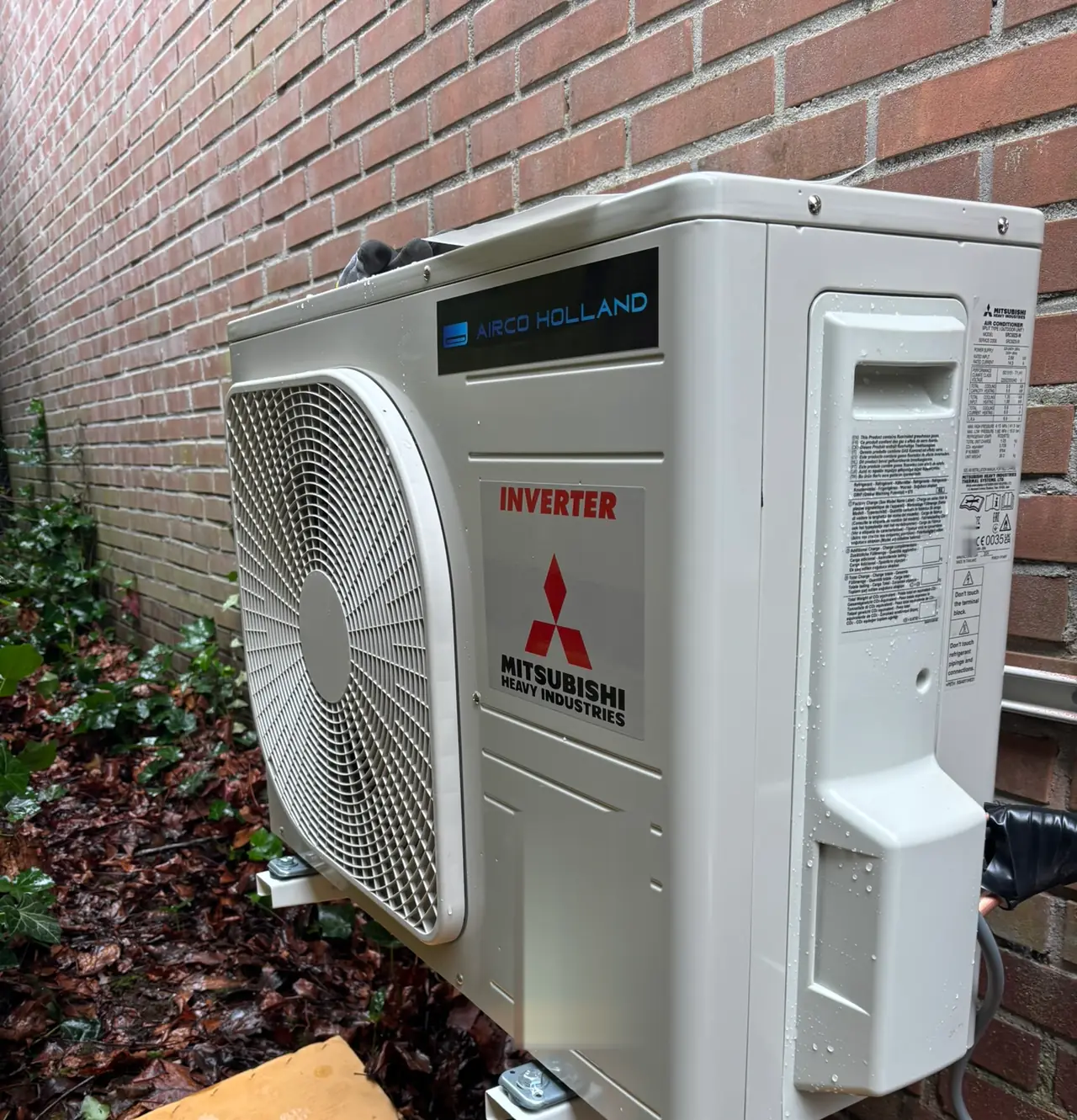 Een buitendeel van Mitsubishi Heavy Industries aan een bakstenen muur, tussen klimop en herfstbladeren.